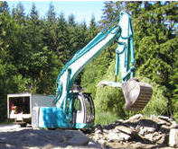 A Torak Services excavator working on a wooded site.