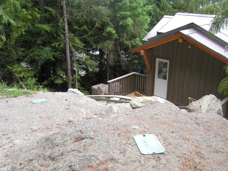 Septic access lids set into a gravel bed on a steep Whistler hillside.