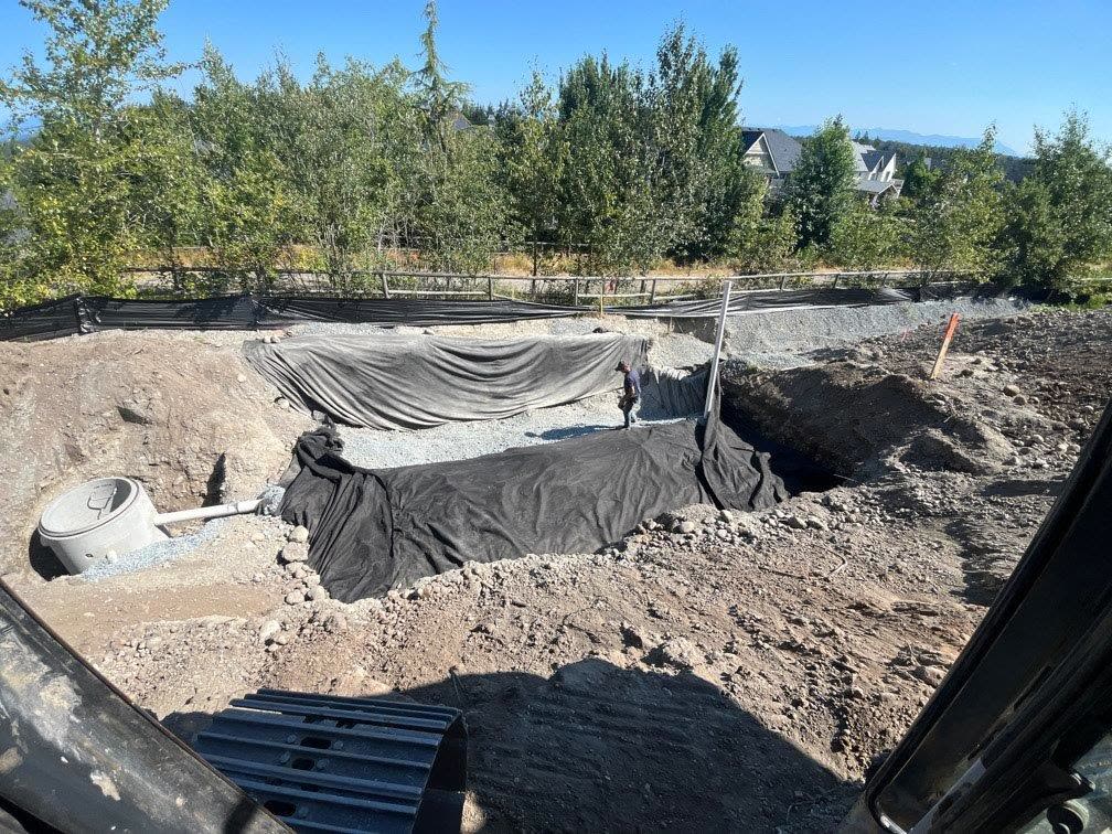 A stormwater rock pit lined with filter fabric and filled with clean drain rock, with an inspection sump at one end.