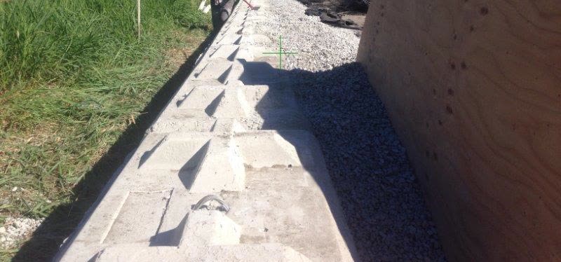 A long lock block retaining wall with drain rock and filter fabric behind it, formwork panel on the right.